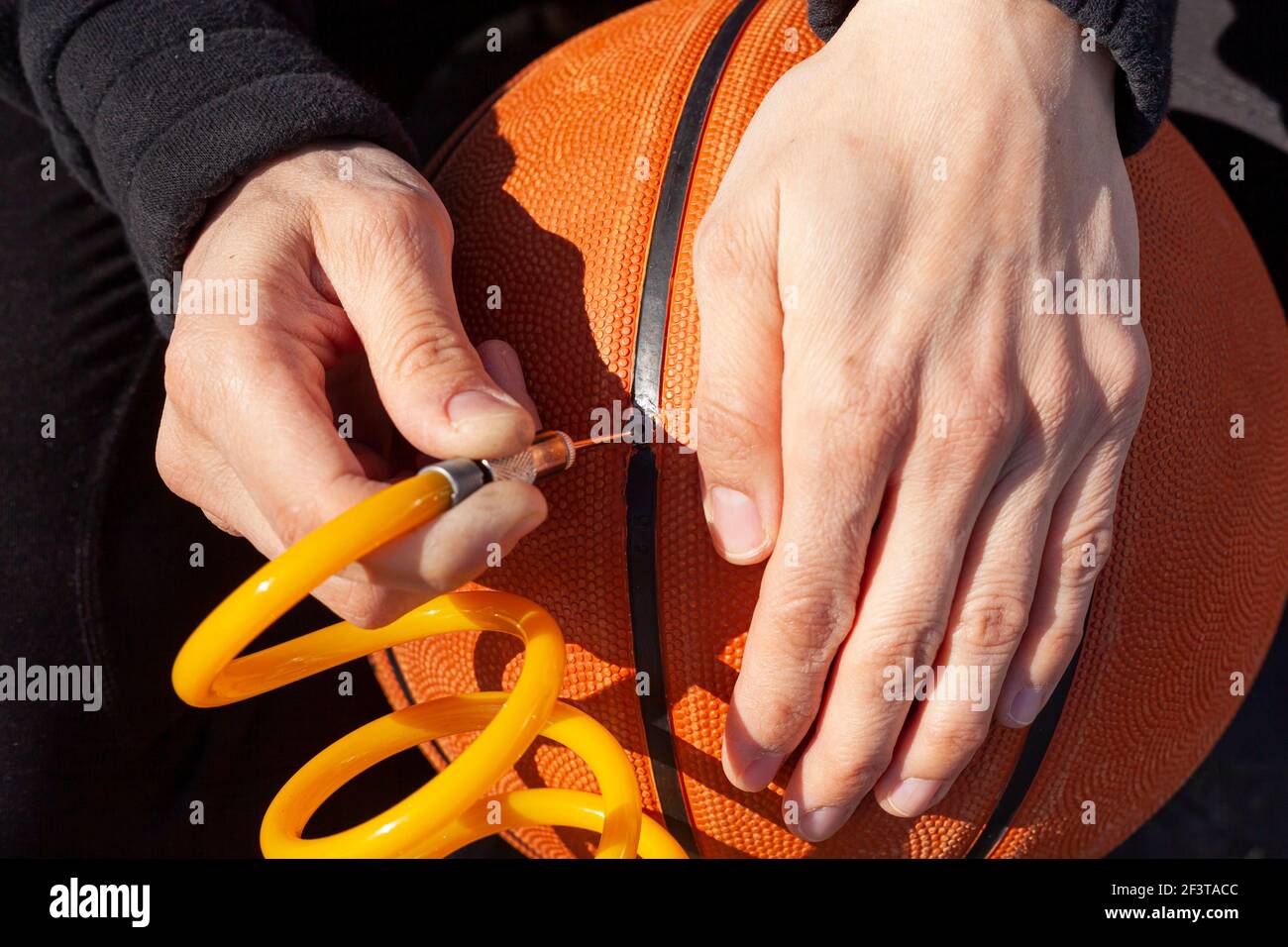 Primo piano immagine che mostra una donna caucasica che tiene un basket e inserendo la punta dell'ago all'estremità del tubo fissato al dispositivo di gonfiaggio pneumatici per auto da 12 v a p. Foto Stock