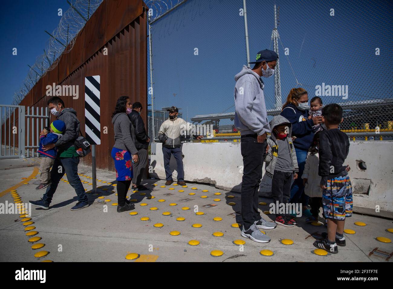 San Ysidro, Messico. 17 Marzo 2021. I migranti provenienti dall'America centrale e i loro figli osservano un esercizio condotto dai membri della polizia di frontiera statunitense (CBP) al valico di San Ysidro contro un potenziale afflusso illegale di migranti. Un giorno prima, l’ex presidente americano Trump ha messo in guardia da una crisi di proporzioni senza precedenti al confine meridionale con il Messico alla luce delle politiche del suo successore Biden. Sono attualmente in fase di segnalazione numeri record di valichi di frontiera illegali, ma presto si otterrà "unità centrale abitacolo, molto peggio", ha detto Trump. Credit: Stringer/dpa/Alamy Live News Foto Stock