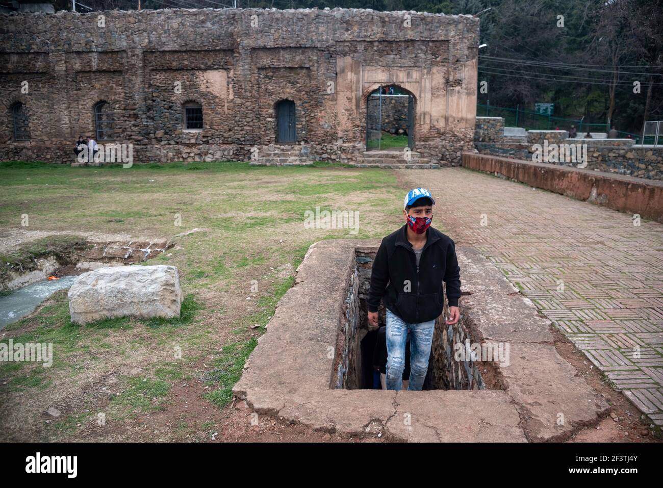 Srinagar, Jammu e Kashmir, India. 15 marzo 2021. Un uomo che indossa una maschera facciale cammina lungo un composto di una moschea costruita da Dara Shikoh nel 1649 DC situato ai piedi di Hari Parbat nel centro della zona di Srinagar. Credit: Idrees Abbas/SOPA Images/ZUMA Wire/Alamy Live News Foto Stock