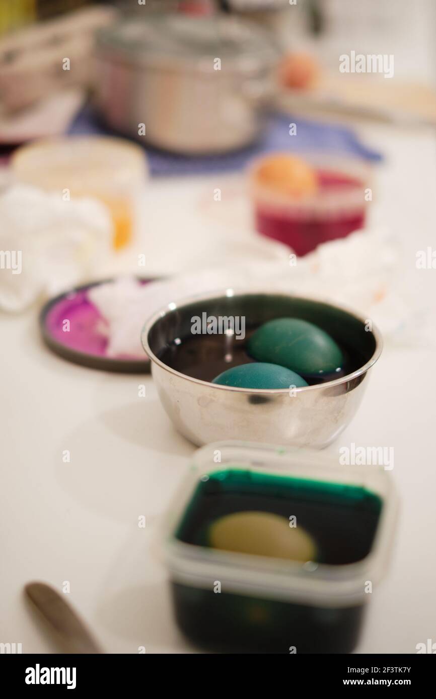 Uova colorate in tinta in plastica e metallo ciotole su una superficie di cucina disordinata, tradizioni di famiglia per Pasqua Foto Stock