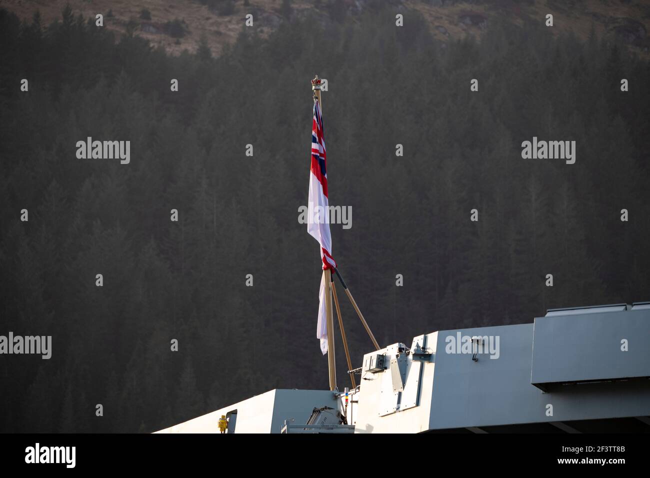 Finnart, Loch Long, Scozia, Regno Unito. 17 Marzo 2021. Bandiera di St Georges Cross. HMS Queen Elizabeth è la più grande e più avanzata nave da guerra mai costruita per la Royal Navy. Sia la regina Elisabetta della HMS (nella foto) che il principe del Galles della HMS sono le bandiere della nazione che pesano in 65,000 tonnellate e misurano 280 metri di lunghezza. La portaerei è attualmente ormeggiato sul lato di Long Loch a Glen Mallan prendendo carburante, munizioni e altre forniture, prima degli esercizi navali che fanno parte del gruppo UK Carrier Strike 2021. La nave dovrebbe partire la domenica. Credit: Colin Fisher/Alamy Live News Foto Stock