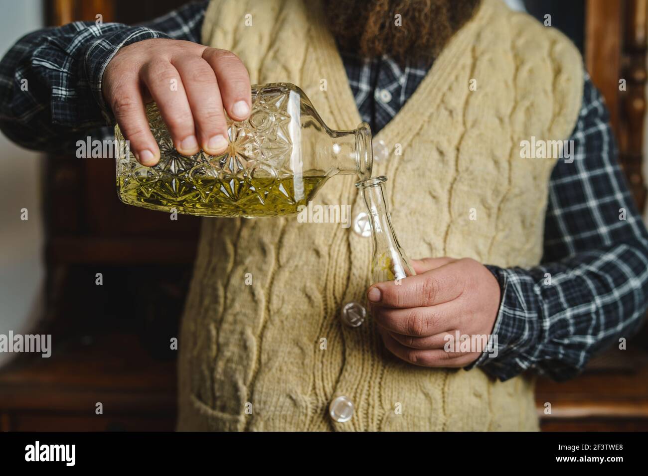 Primo piano sulle mani di un uomo sconosciuto che versa il tradizionale serbo bosniaco croato o macedone bere alcol brandy rakija o slivovitza realizzato in prugna i. Foto Stock