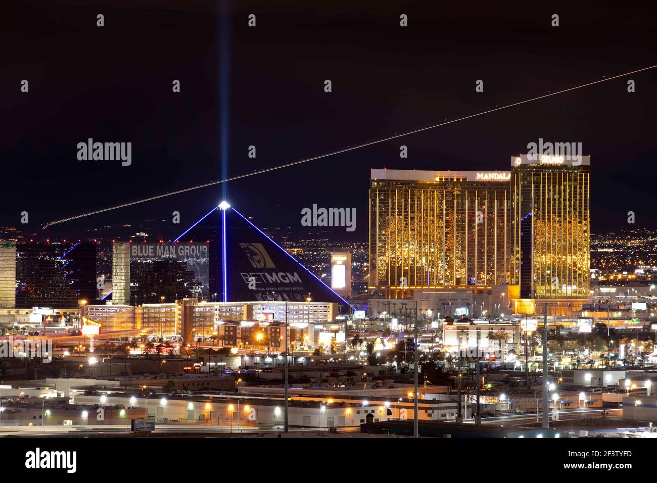 Las Vegas, Nevada, Stati Uniti. 11 Marzo 2021. In una lunga esposizione, le luci da un getto che decollo da McCarran International Airport striscia dietro il Luxor Hotel & Casino, a sinistra, e Mandalay Bay Resort e Casino di notte. Credito: K.C. Alfred/ZUMA Wire/Alamy Live News Foto Stock