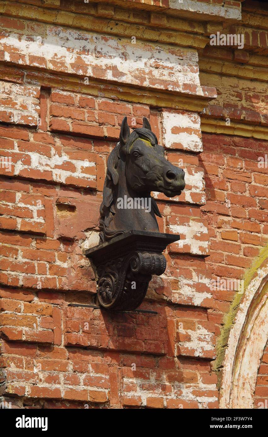 Testa di cavallo di metallo sulla facciata di una ex e abbandonata fabbrica di cavalli del 19 ° secolo (regione di Pskov, Russia) Foto Stock