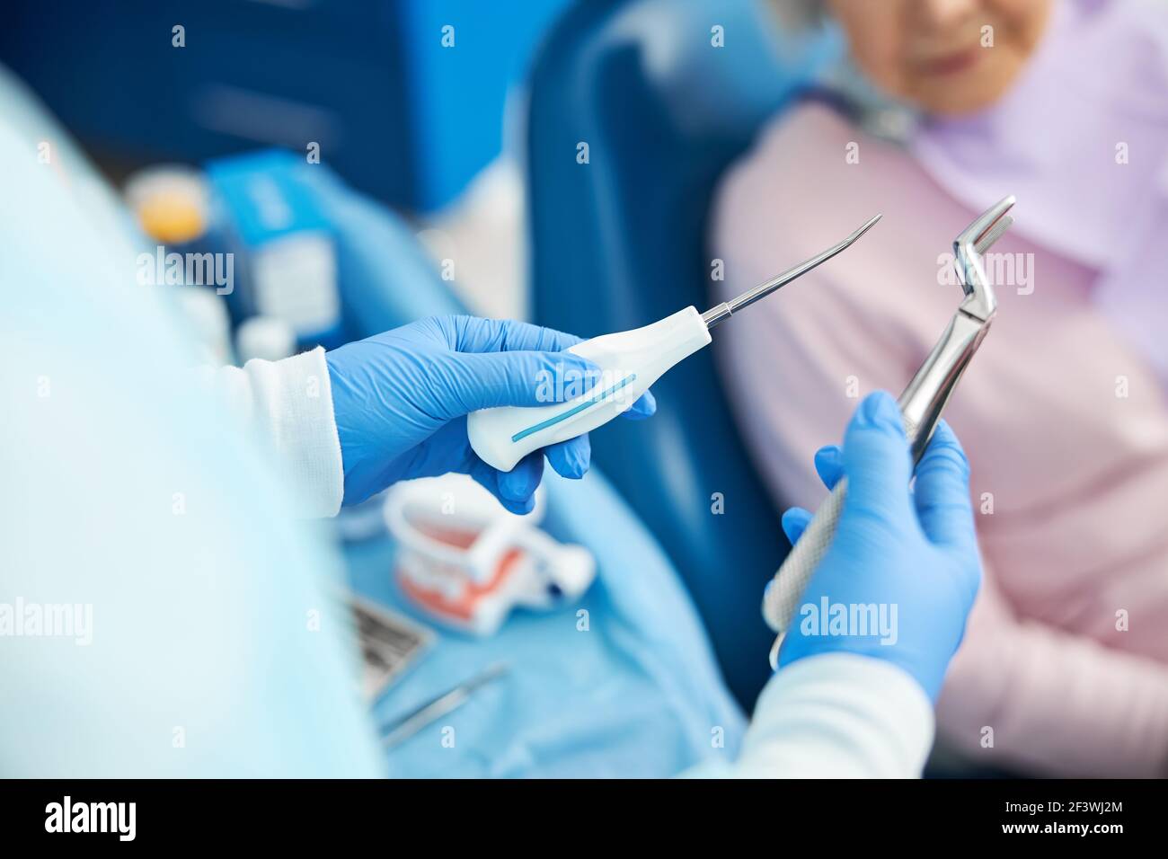 Il dipendente dentista maschile sta dimostrando strumenti di estrazione Foto Stock