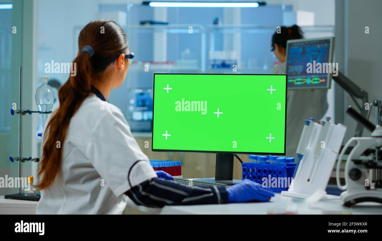 Donna ricercatore che scrive al computer con schermo verde mockup display,  modello in laboratorio di scienza