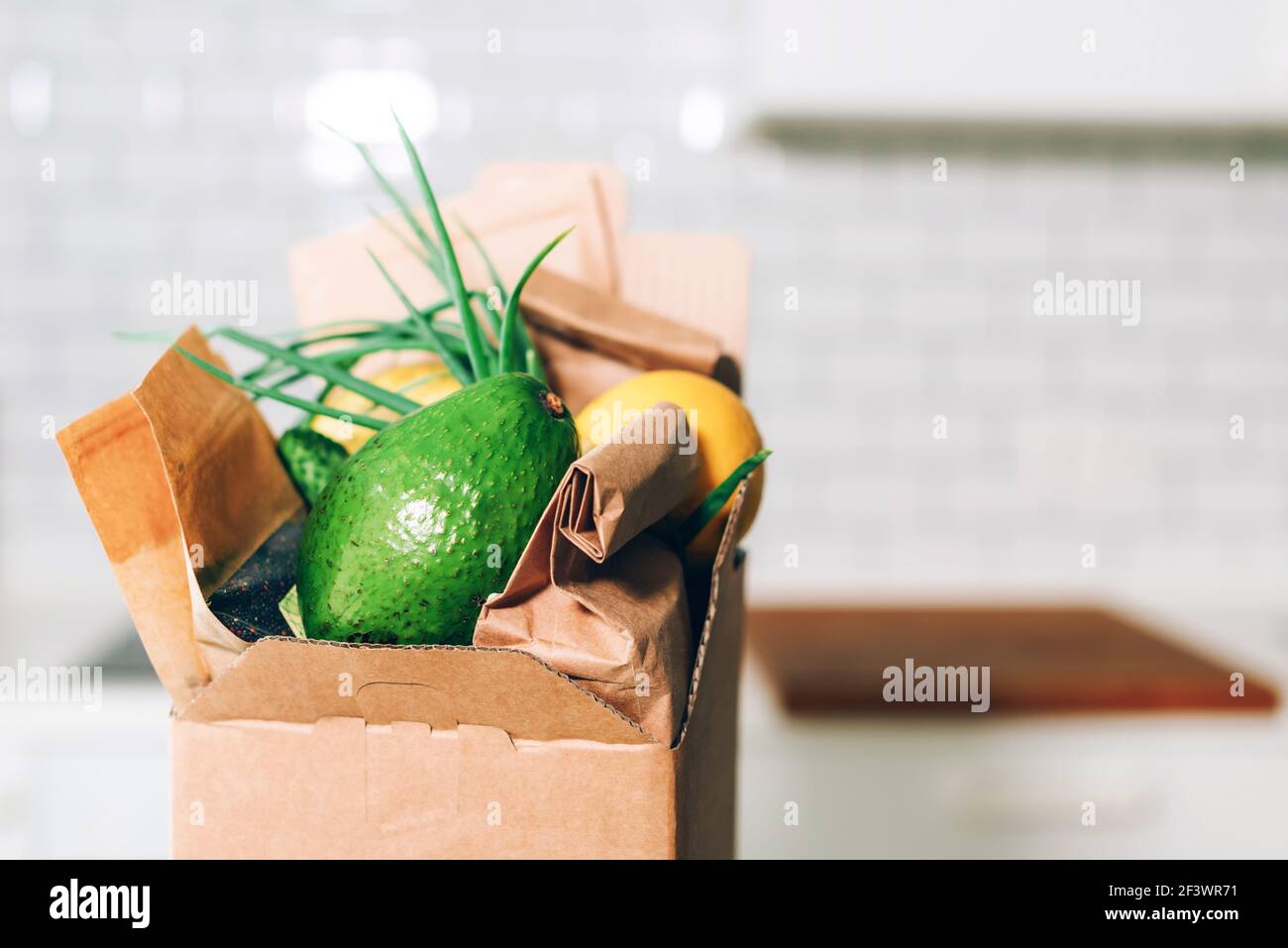 Scatola di donazione con cibo sano su sfondo bianco della cucina. Spazio di copia. Servizio di consegna di cibo durante la pandemia di coronavirus. Shopping online. Cibo Foto Stock