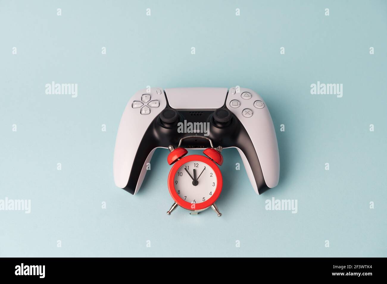 Console videogiochi gamepad su sfondo blu con sveglia rossa. Tim per  giocare. Problema del giocatore in dipendenza dal gioco Foto stock - Alamy