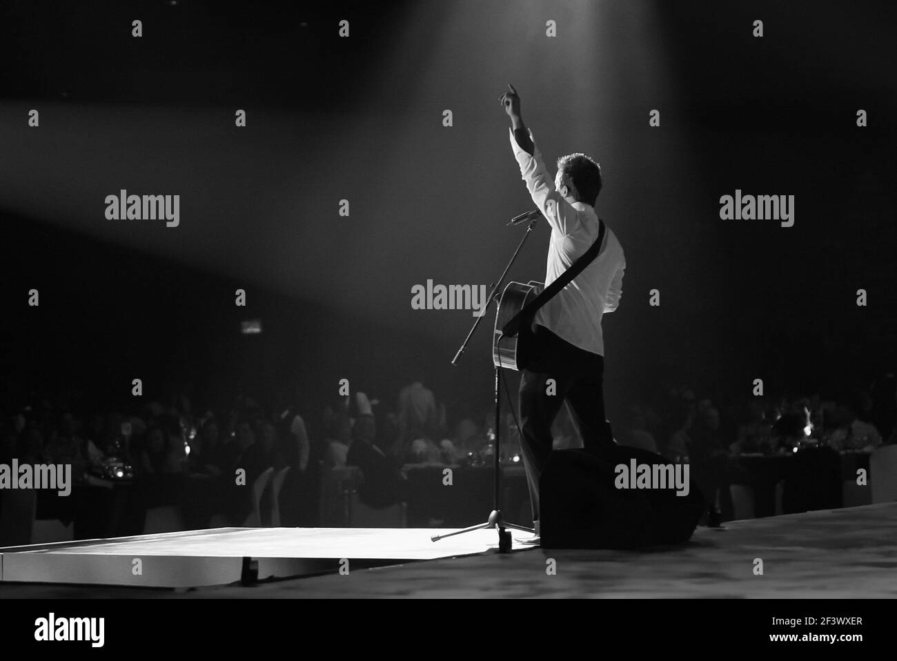 Un cantante con chitarra in piedi sul palco del concerto Foto Stock