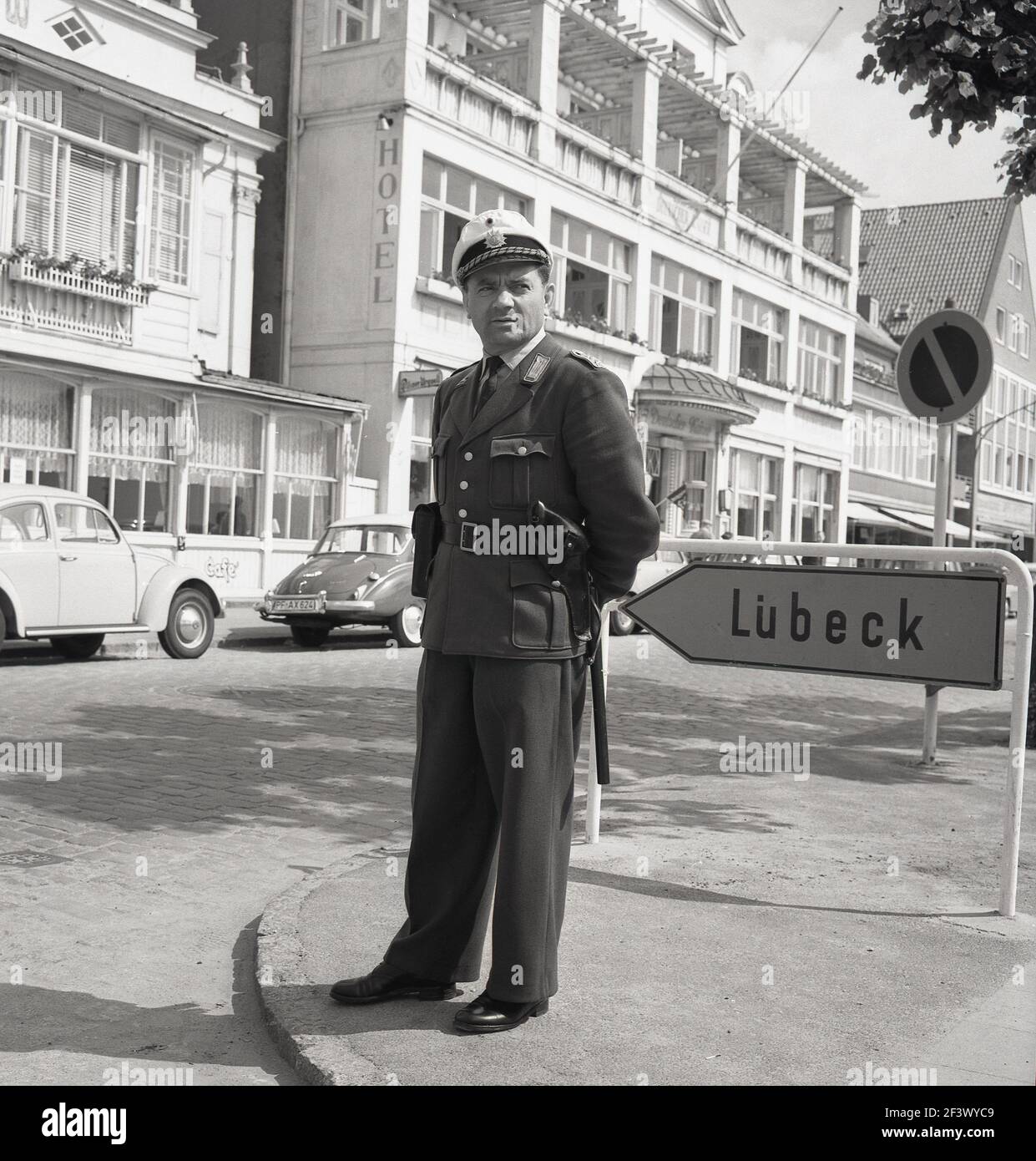 1960s, foto storica di J Allan Cash di un poliziotto tedesco in uniforme, con cappello e trunkeon, che si trova all'angolo di una strada vicino a Lubecca, la seconda città più grande dello stato dello Schleswig-Holstein, in Germania. Foto Stock