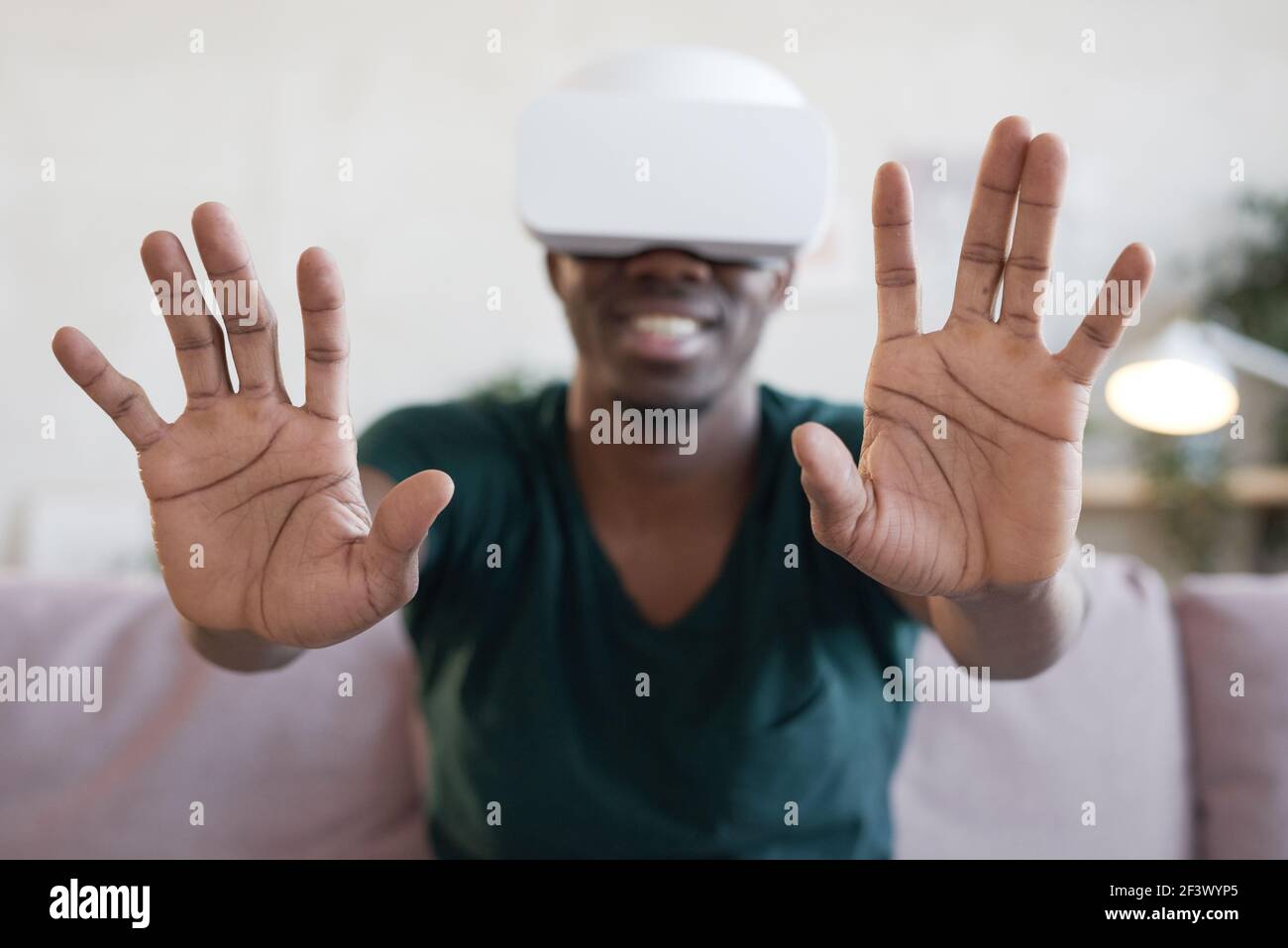 Uomo africano in occhiali che gioca e gesturing durante il video gioco sul divano Foto Stock