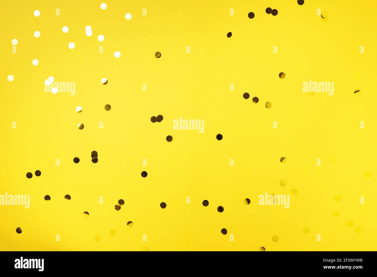 Confetti dorati su sfondo giallo con bokeh chiari. Felice festa di festa di nuovo anno. Saluto e congratulazioni concetto. Sfondo festivo con Foto Stock