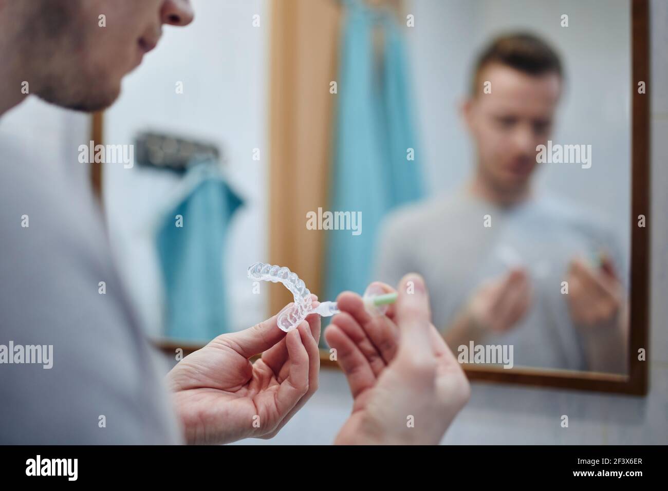 Giovane uomo che prepara vassoio in silicone per la siringa di gel sbiancante e sbiancante dei denti. Temi salute dentale, cura e bellezza. Foto Stock