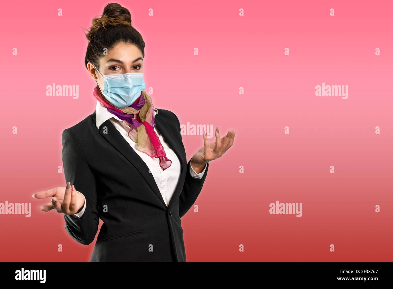 Un bellissimo assistente di volo con sciarpa multicolore e maschera, su sfondo rosso. Foto perfetta per viaggi, vacanze e lavoro durante la pandemia. Foto Stock