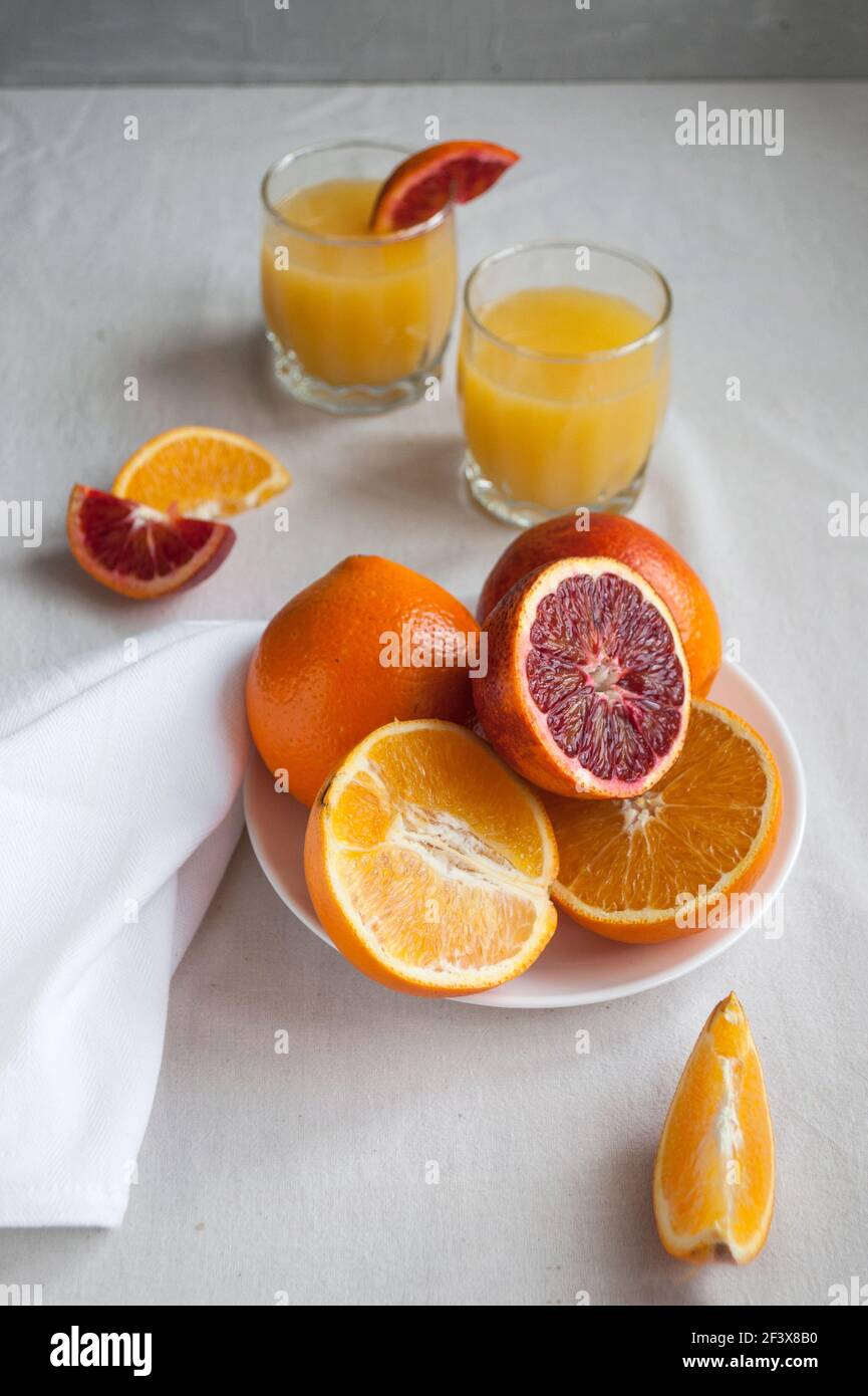 Piatto di arance e arance fresche, dolci e succose, intere e tagliate su un  piatto bianco. Succo d'arancia fresco con arance a fette Foto stock - Alamy