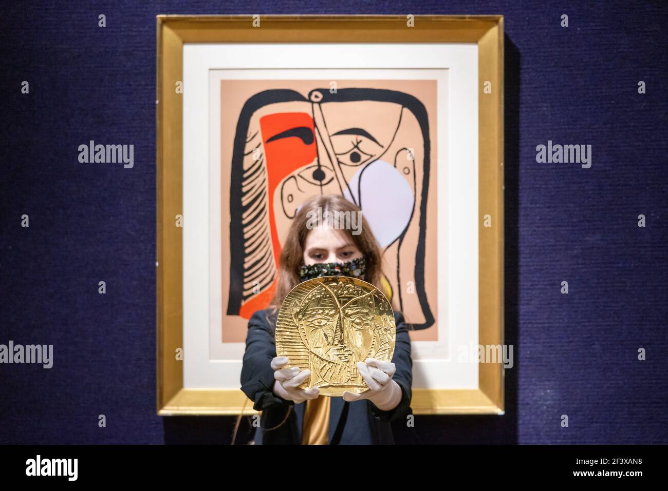 Un dipendente di Bonhams detiene la "Visage de Faune", repoussŽ una piastra d'oro da 22 carati prodotta da Pablo Picasso e dall'orafo Franois Hugo che ha una stima di £250,000-350,000, insieme a "Portrait de Jacqueline aux Cheveux Lisses" in occasione di una telefonata a Bonhams a Londra, prima della loro prossima vendita Picassomania, Che si svolge il 23 marzo. Data immagine: Giovedì 18 marzo 2021. Foto Stock
