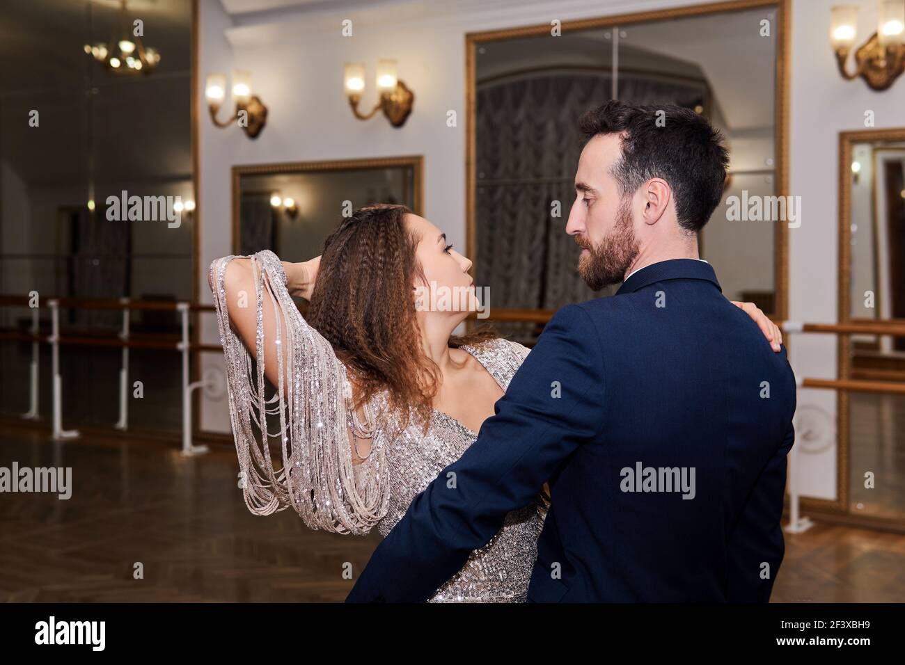 una coppia di adulti che danzano con un partner espressivo nella sala da ballo vuota Foto Stock