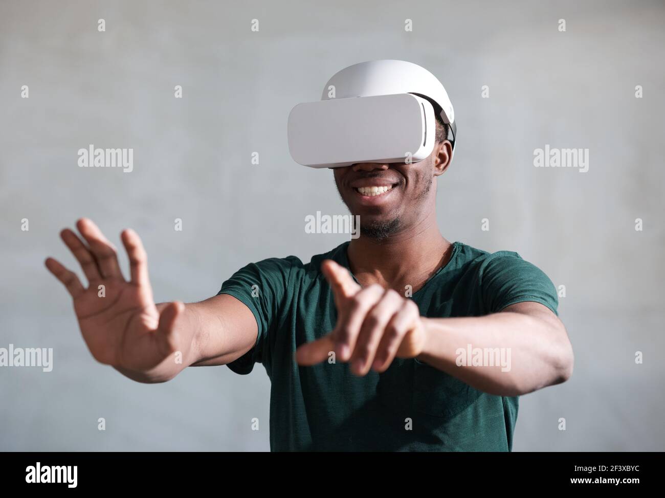 Giovane uomo africano che gioca giochi da console con visore vr isolato su sfondo grigio Foto Stock
