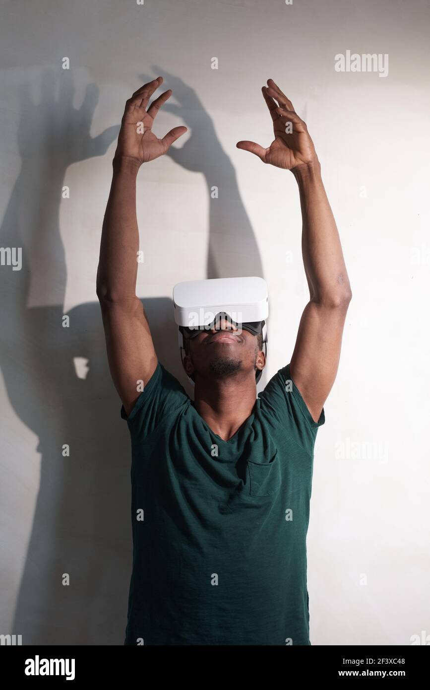 Giovane uomo con occhiali di realtà virtuale che toccano l'aria durante L'esperienza di realtà virtuale a casa tua Foto Stock