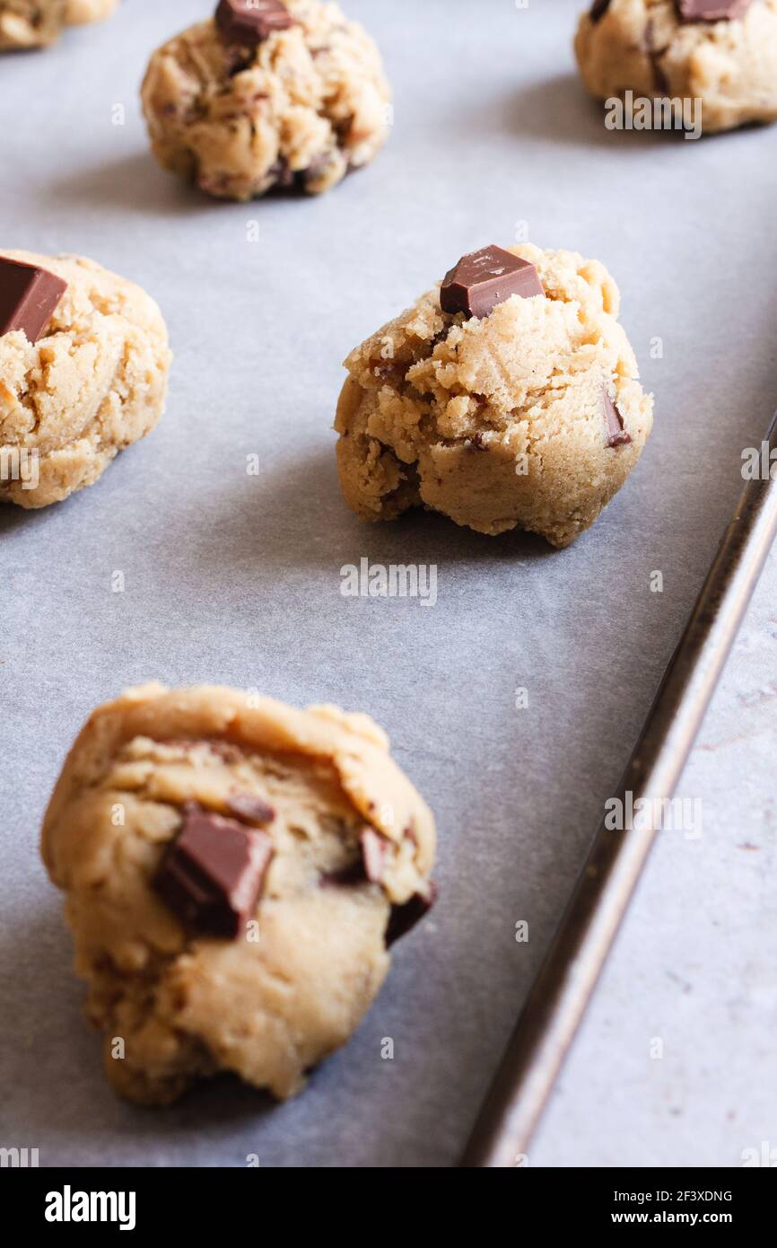 Pasta di biscotti grezza con scaglie di cioccolato ricoperta su un vassoio da forno Foto Stock