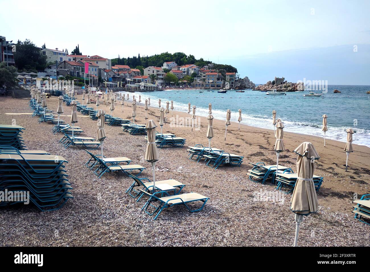 Spiaggia deserta con lettini e ombrelloni vicino al mare. Autunno in Montenegro. Foto Stock