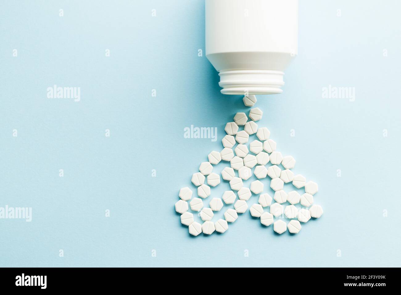 Pillole di medicina forma del cuore con bottiglia su sfondo blu Foto Stock