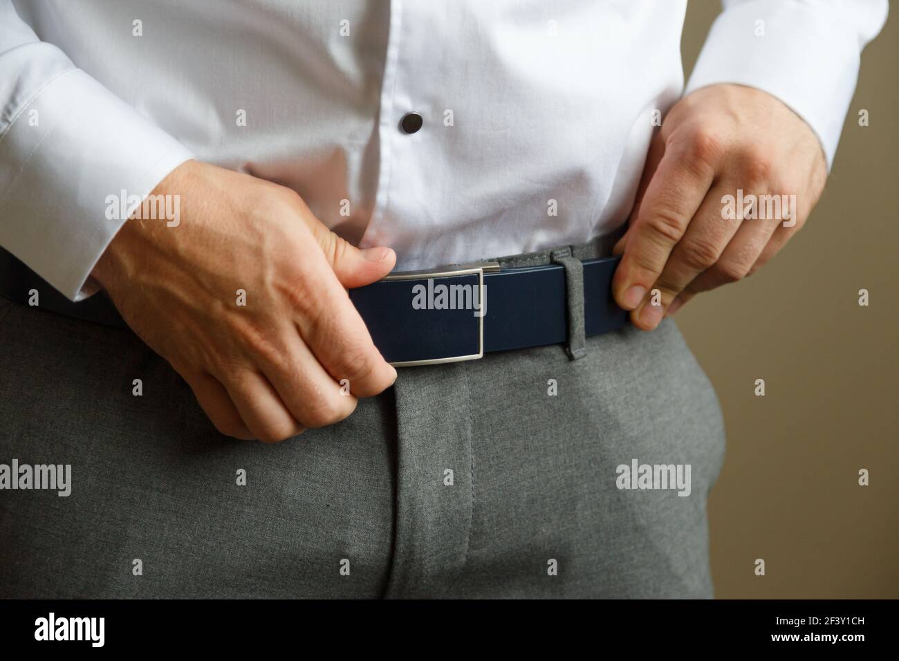 Un uomo con pantaloni blu e una camicia bianca abbelliva una cintura per  pantaloni marrone in pelle. Ha un orologio sulla sua mano Foto stock - Alamy