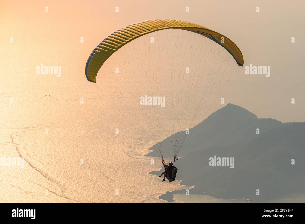 Parapendio nel cielo. Parapendio tandem che sorvola il mare con le montagne al tramonto. Veduta aerea del parapendio e della Laguna Blu a Oludeniz, Mugla, Foto Stock