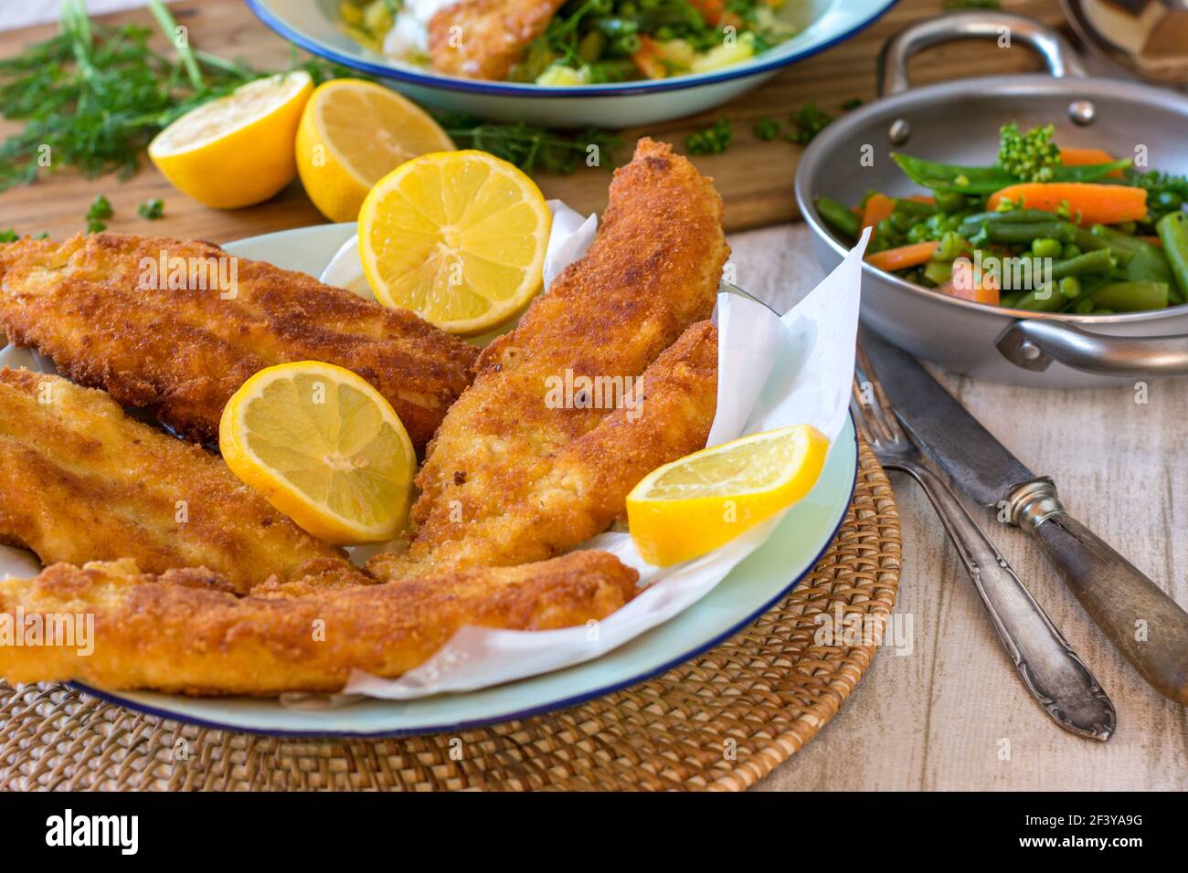 Un piatto con filetto di rossfish fresco impanato su un tavolo da cucina rustico Foto Stock