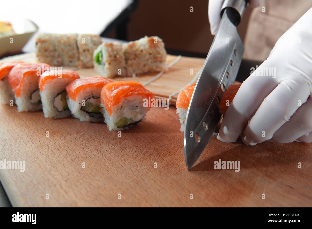 Il maestro del sushi prepara piatti tradizionali giapponesi. Taglia il sushi. Foto Stock