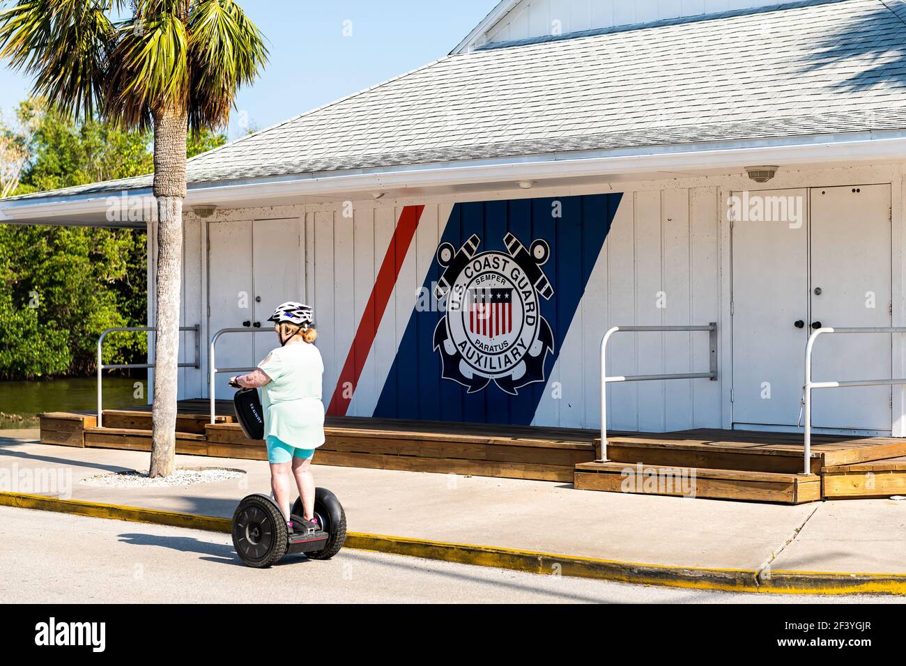 Napoli, USA - 30 aprile 2018: Florida golfo di città del messico con donna che cavalcano segway da US Coast Guard edificio ausiliario segno per la guardia costiera pattuglia Foto Stock