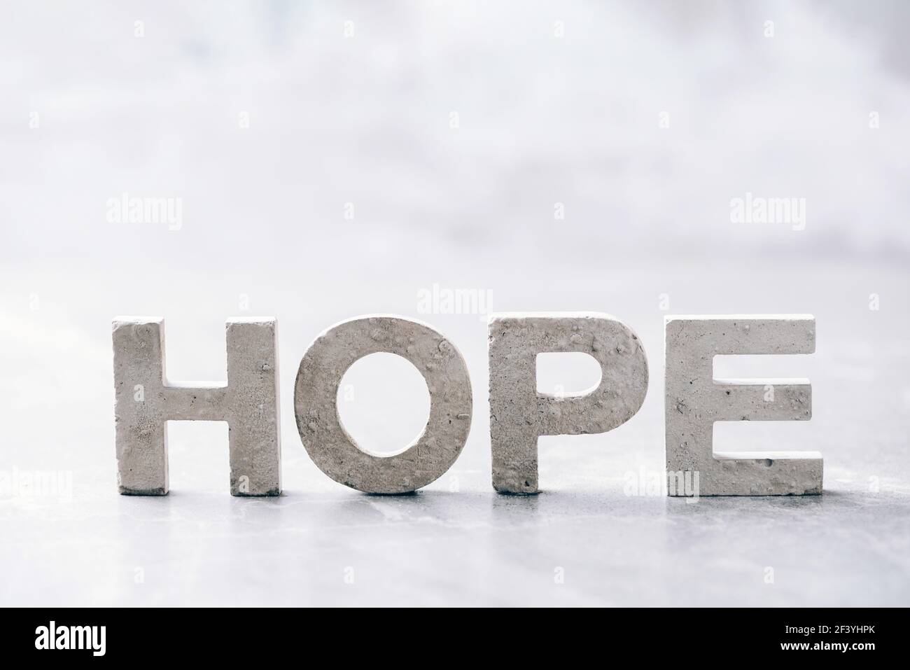 Parola SPERANZA fatta con lettere di cemento su sfondo grigio marmo. Spazio di copia. Promemoria biblico, spirituale o cristiano Foto Stock