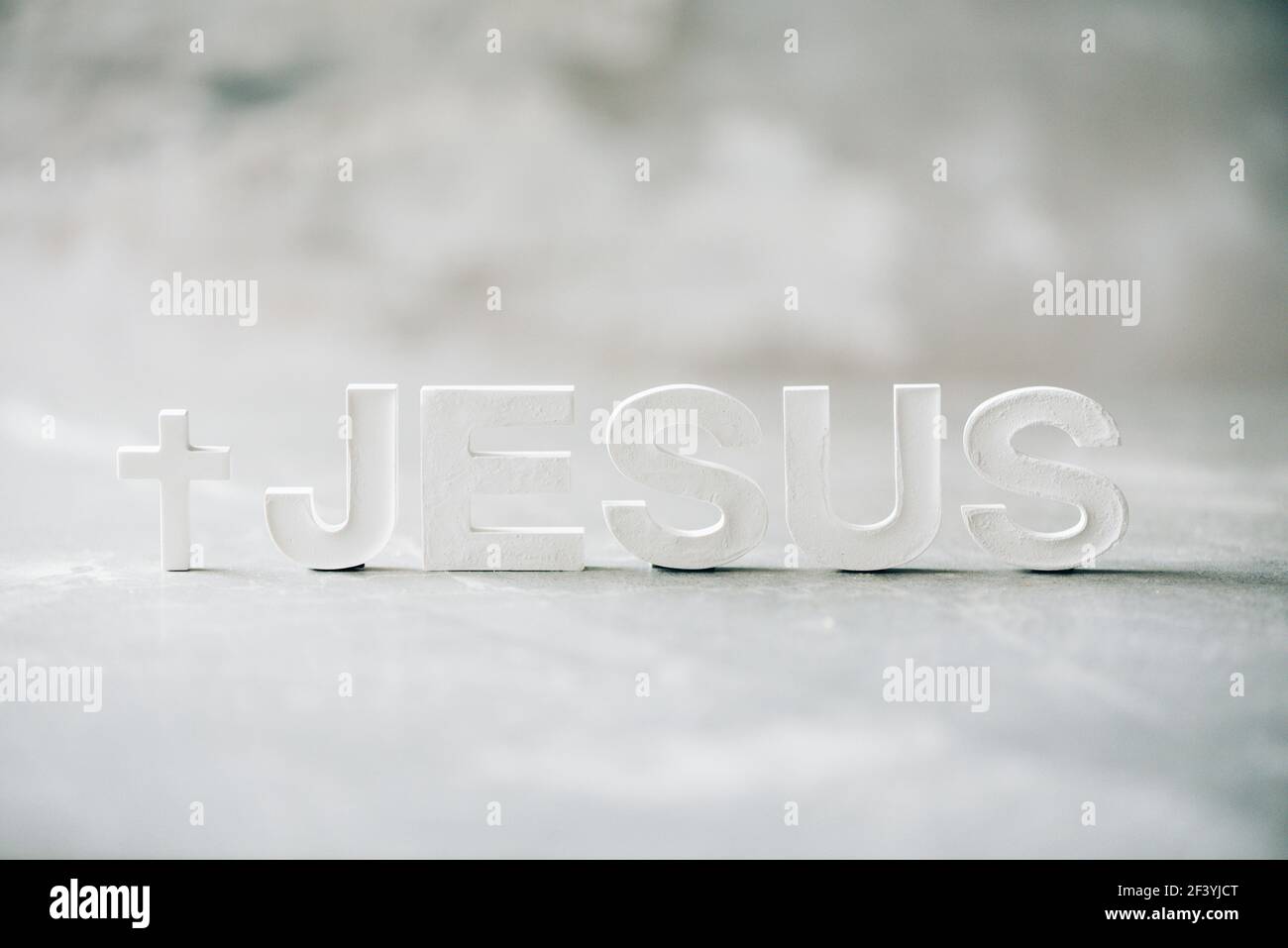 Nome GESÙ fatto con lettere di cemento su sfondo di marmo grigio. Spazio di copia. Promemoria biblico, spirituale o cristiano Foto Stock