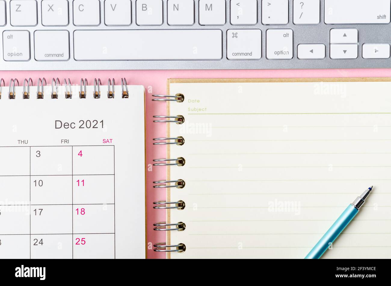 Calendario di dicembre 2021 con note book su sfondo rosa. Foto Stock