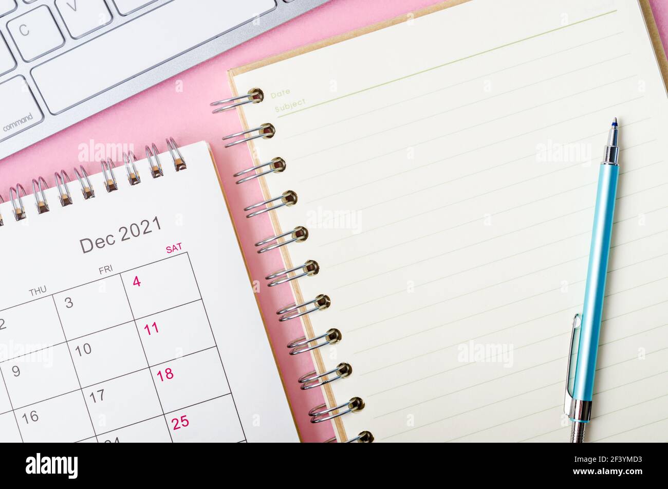 Calendario di dicembre 2021 con note book su sfondo rosa. Foto Stock
