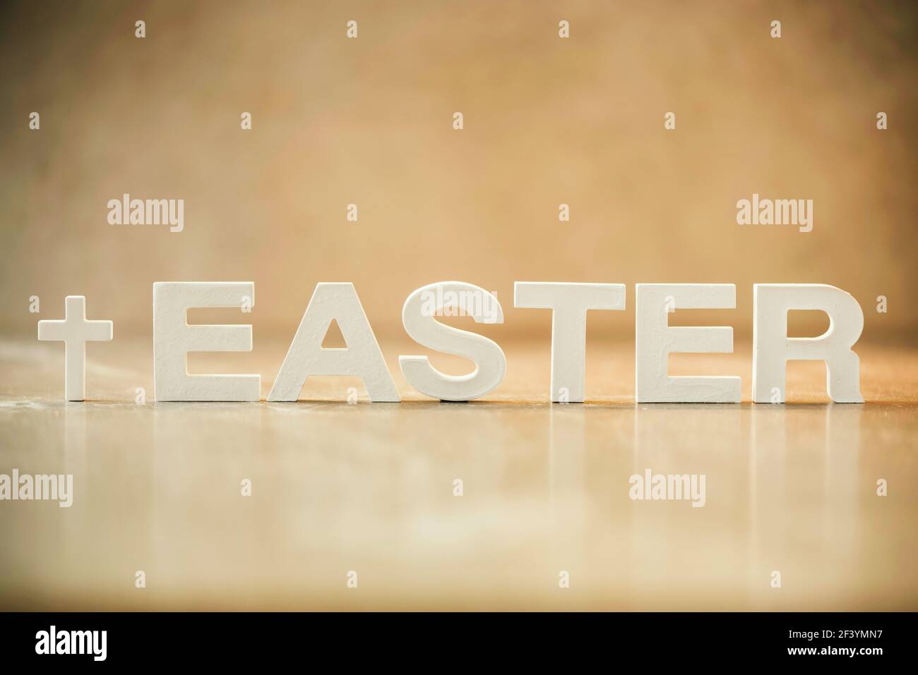Parola Pasqua fatta con lettere di cemento su sfondo di marmo arancione. Promemoria biblico, spirituale o cristiano. Concetto di Pasqua cristiana. Crocifissione Foto Stock