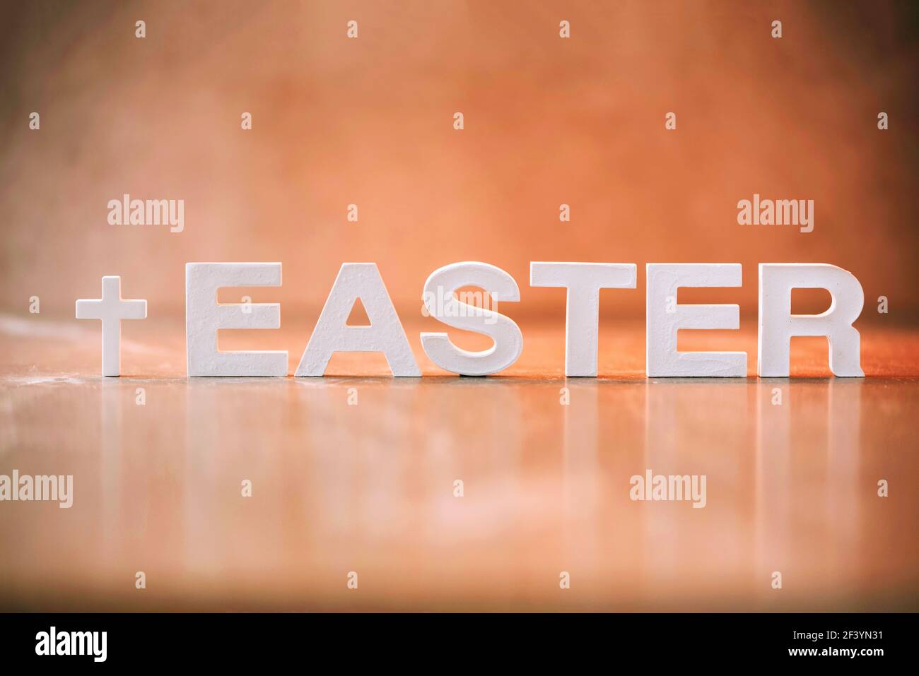 Parola Pasqua fatta con lettere di cemento su sfondo di marmo arancione. Promemoria biblico, spirituale o cristiano. Concetto di Pasqua cristiana. Crocifissione Foto Stock