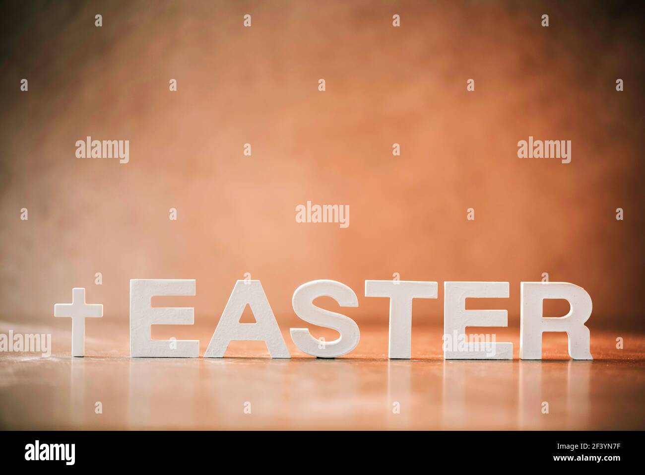 Parola Pasqua fatta con lettere di cemento su sfondo di marmo arancione. Promemoria biblico, spirituale o cristiano. Concetto di Pasqua cristiana. Crocifissione Foto Stock