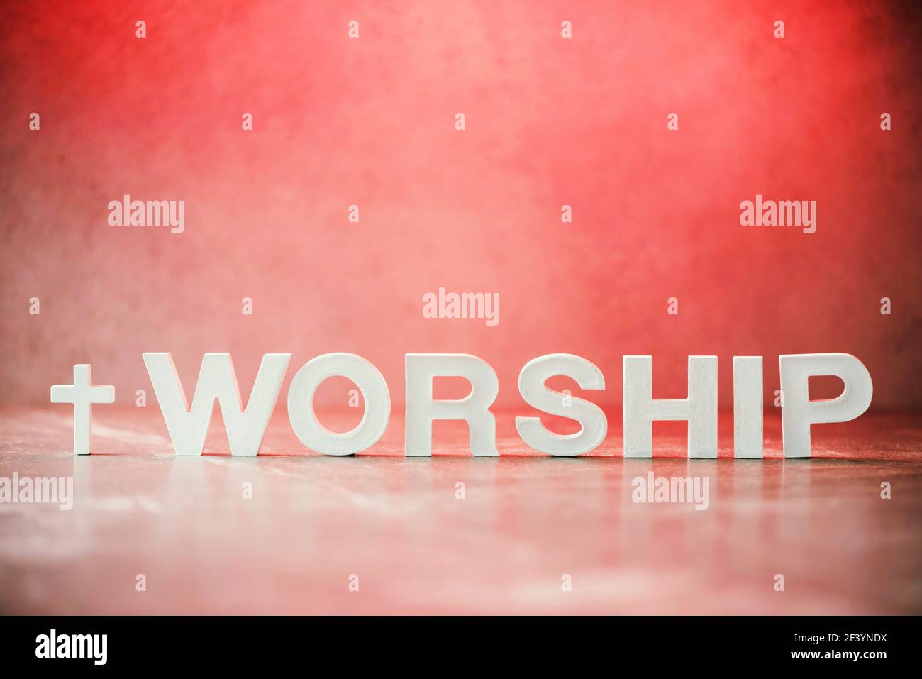 Adorazione di parola fatta con lettere di cemento su sfondo di marmo rosso. Spazio di copia. Promemoria biblico, spirituale o cristiano. Venerdì Santo, giorno di Pasqua Foto Stock