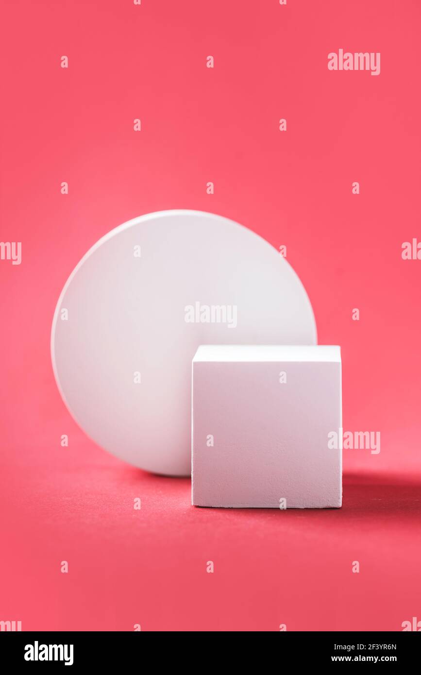 Podio astratto a forma geometrica vuota per prodotto su sfondo rosso pastello. Spazio di copia. Cubo bianco su sfondo rosa. Modello a piedistallo per la pubblicità Foto Stock