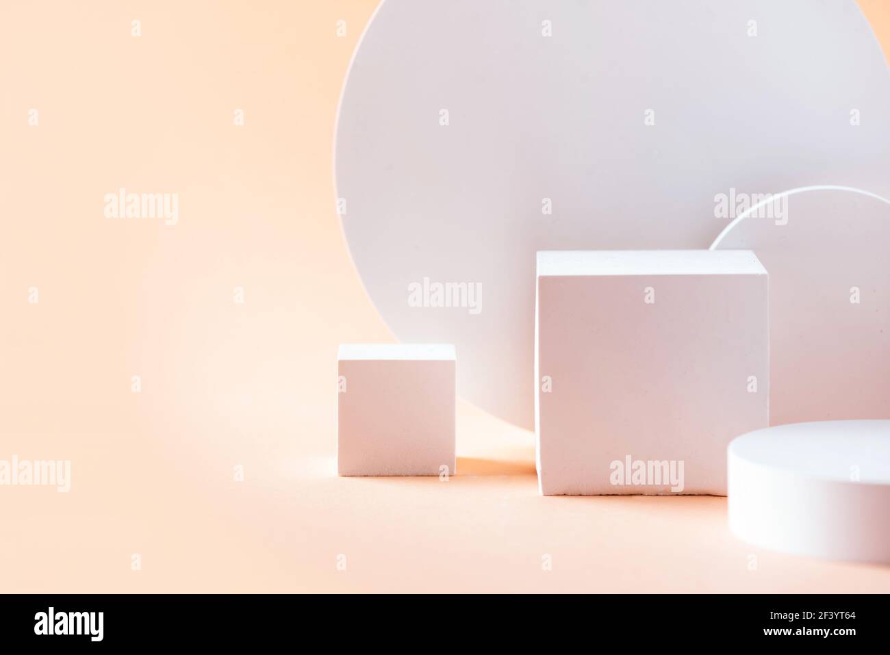 Podio bianco dalle forme geometriche per l'esposizione dei prodotti su sfondo beige. Palco monocromatico, stand per la promozione del prodotto in stile minimale. Spazio di copia per Foto Stock