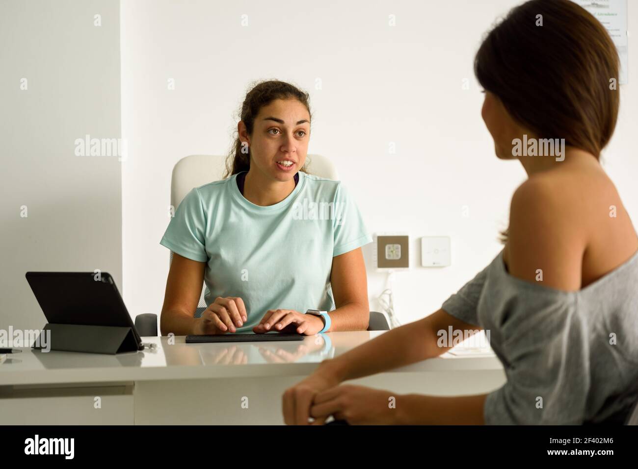 Fisioterapista femmina spiegando la diagnosi per il suo paziente. Brunette donna avente la consultazione con la ragazza in ufficio medico. Foto Stock