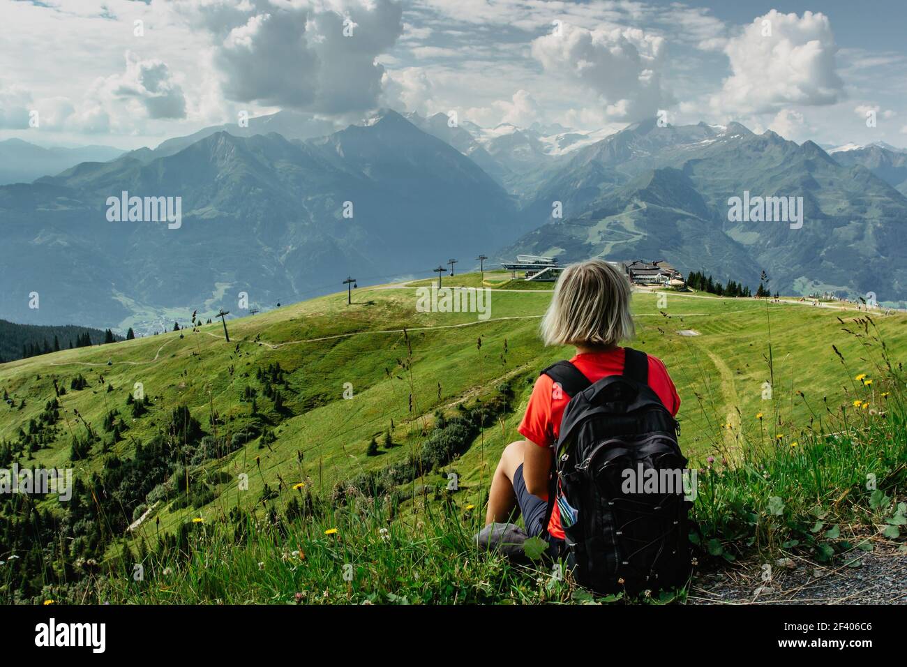 Bionda ragazza godendo di vista durante il trekking nelle Alpi, Austria.Majestic cime di montagne, prati verdi, vista della valle. Attivo Happy Backpacker.Travel Foto Stock