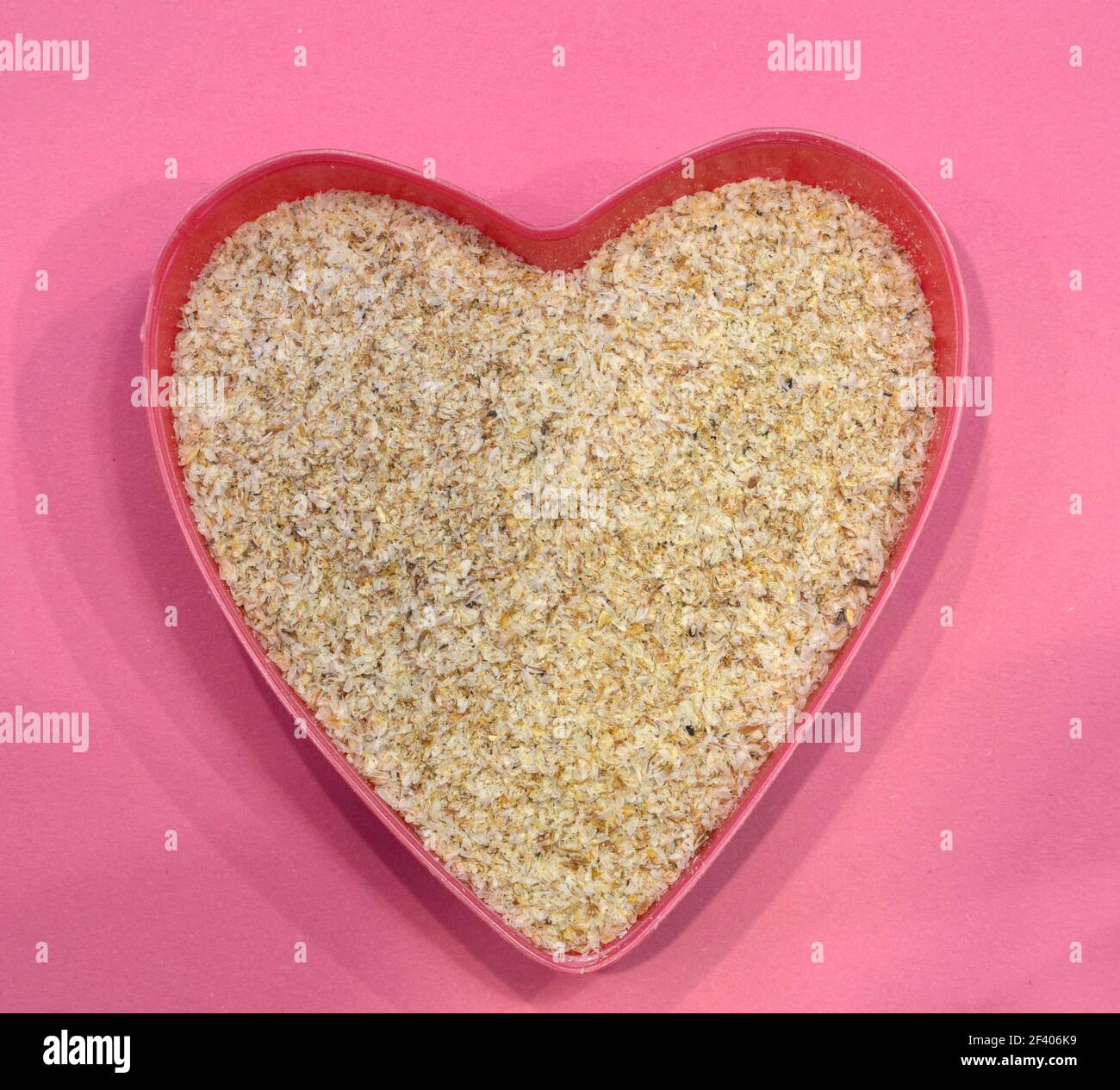 Psyllium a forma di cuore su sfondo rosa, vista dall'alto. Semi di psyllium di cibo eccellente, ingrediente di dieta del keto. Concetto di cibo sano Foto Stock