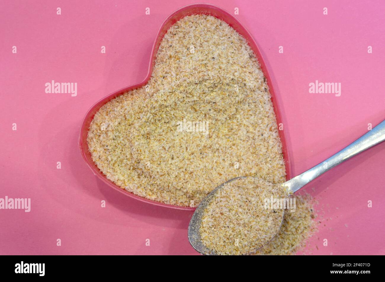 Psyllium a forma di cuore su sfondo rosa, vista dall'alto. Semi di psyllium di cibo eccellente, ingrediente di dieta del keto. Concetto di cibo sano Foto Stock