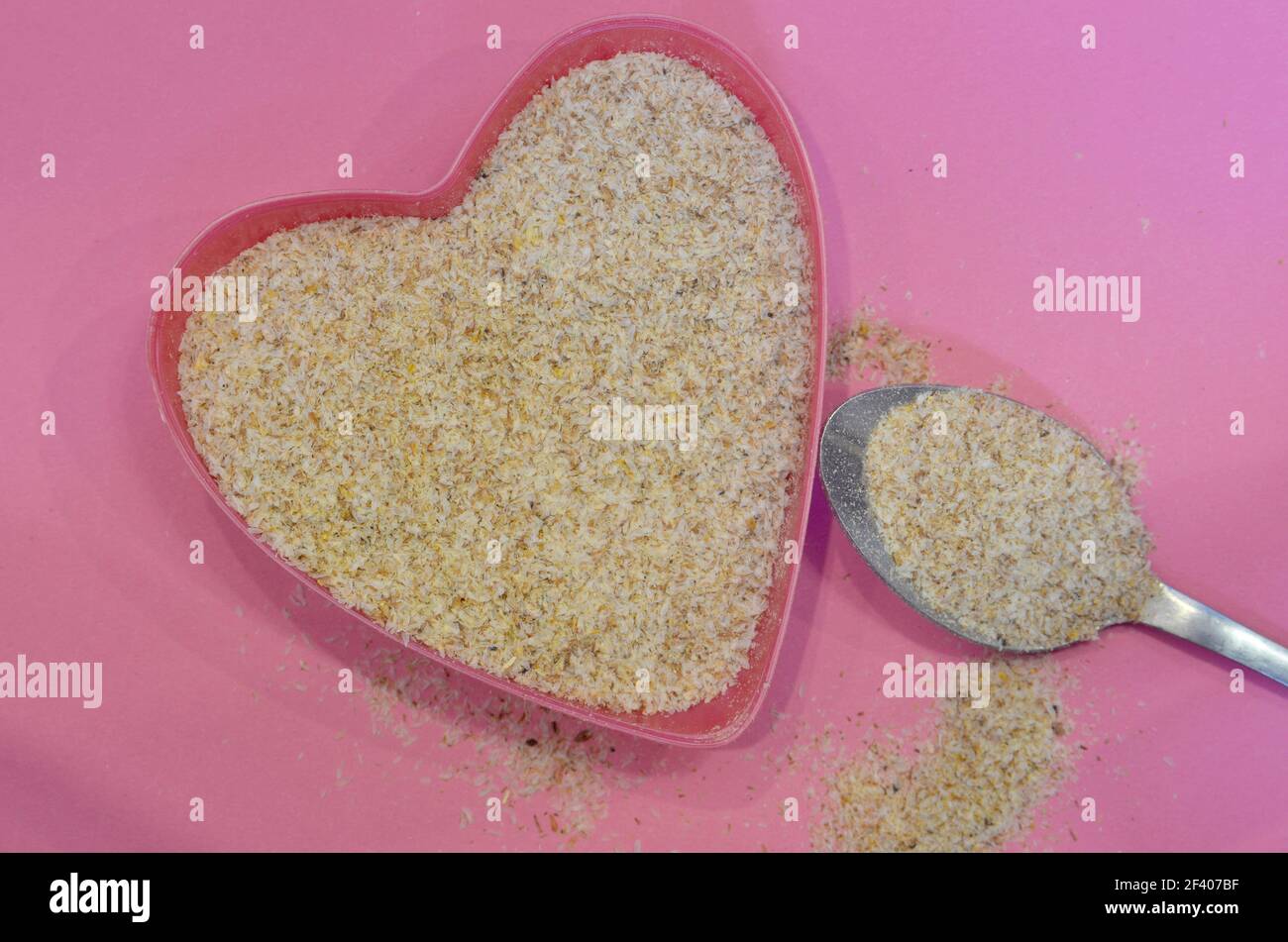 Psyllium a forma di cuore su sfondo rosa, vista dall'alto. Semi di psyllium di cibo eccellente, ingrediente di dieta del keto. Concetto di cibo sano Foto Stock