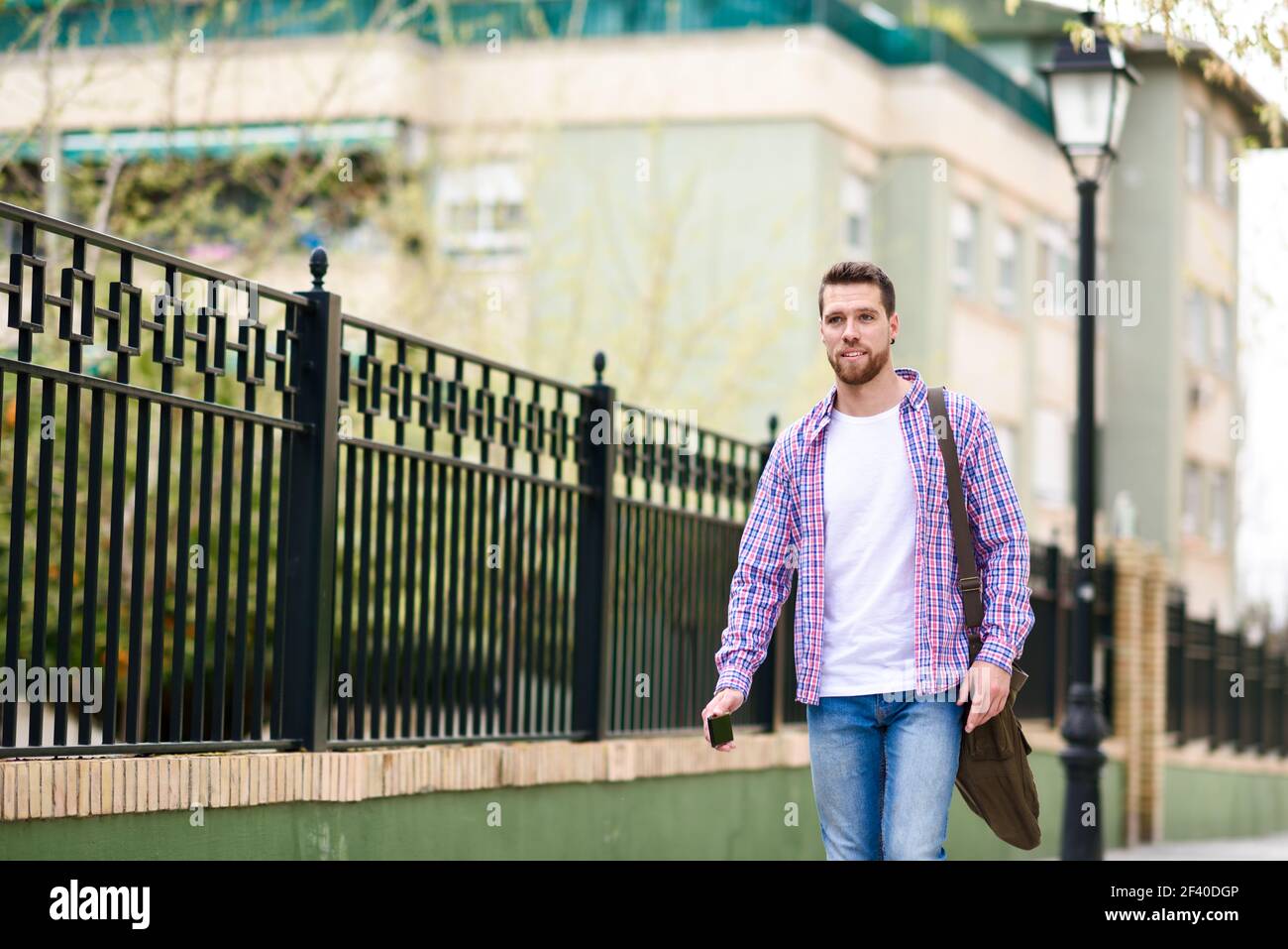 Giovane uomo barbuto camminando in background urbano. Traveler di indossare un abbigliamento informale. Il concetto di stile di vita. Foto Stock