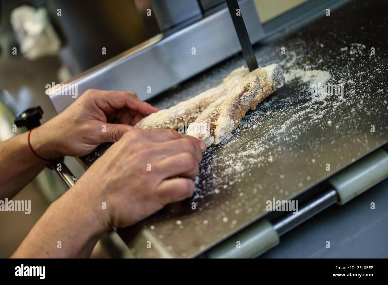 Close-up di macellaio maschio Prosciutto taglio le ossa in una macchina di taglio all'interno di un negozio di macellaio. Foto Stock