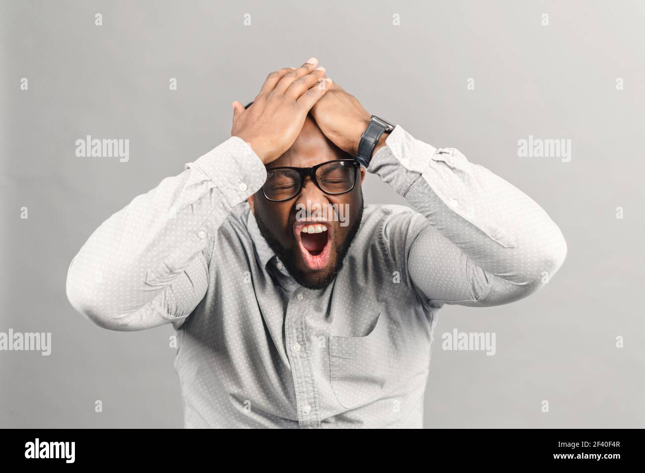 Frustrato afroamericano ragazzo urlando no, stressante nero che tiene l'uomo ha panico attacco, depressione, un sacco di problemi si sono accumulati, studio girato isolato su grigio Foto Stock