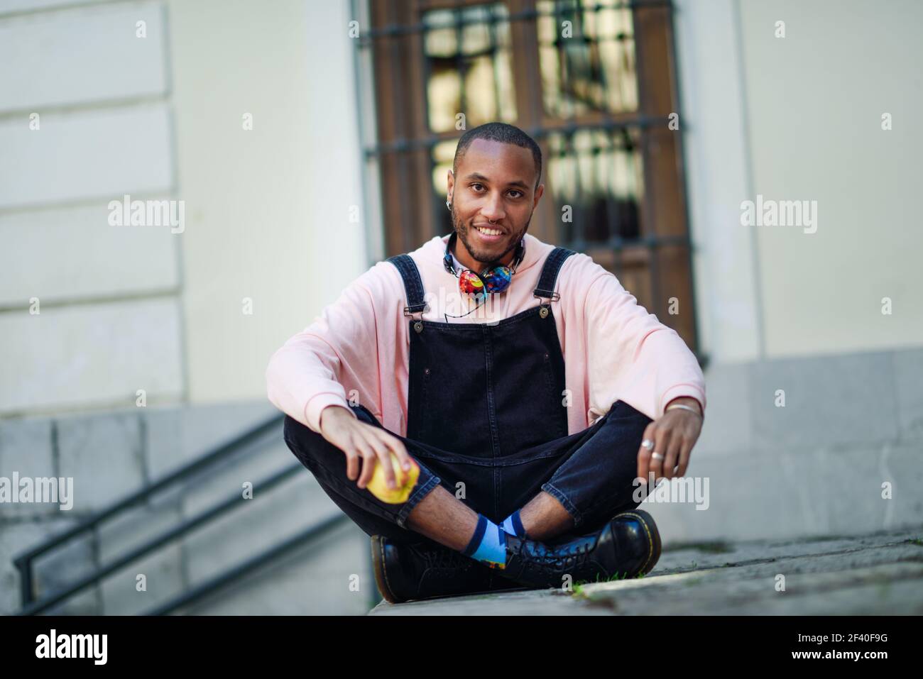 Giovane uomo nero una mela seduto su fasi urbane. Il concetto di stile di vita. Foto Stock